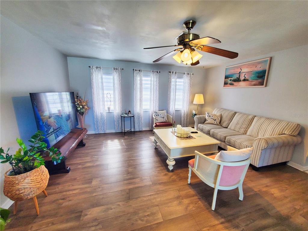 A living room features wood-look flooring, a ceiling fan, a sofa, and a television — 4 GOLFVIEW ROAD, ROTONDA WEST, FL