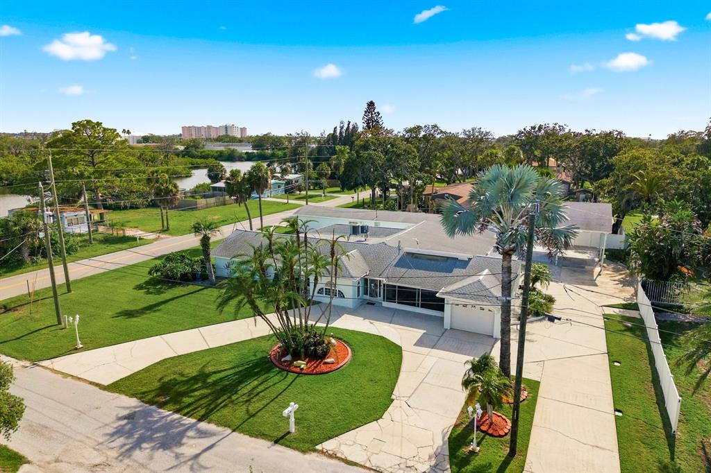 A single-story house with a light-colored exterior, a two-car garage, and a palm tree garden — 6309 WERNER AVENUE, NEW PORT RICHEY, FL