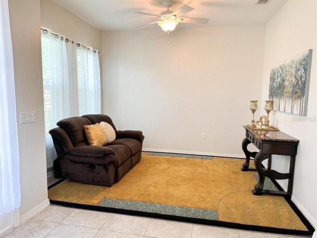 A living room features a gray sofa, a round wooden coffee table, and yellow curtains — 603 BRITTLE FERN AVENUE, DELAND, FL
