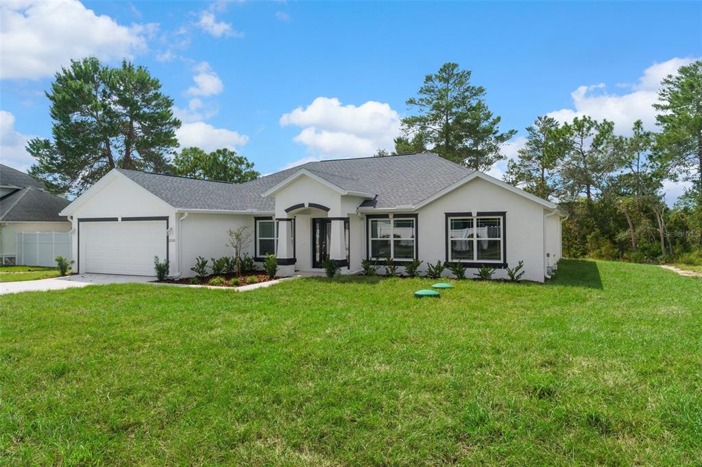 A single-story white house with a gray shingled roof and a two-car garage — 13058 KITTIWAKE ROAD, WEEKI WACHEE, FL