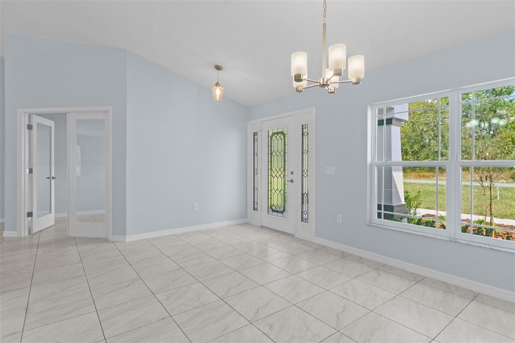 A bright entryway features light blue walls, white tile flooring, a chandelier, and a glass-paneled door — 13058 KITTIWAKE ROAD, WEEKI WACHEE, FL