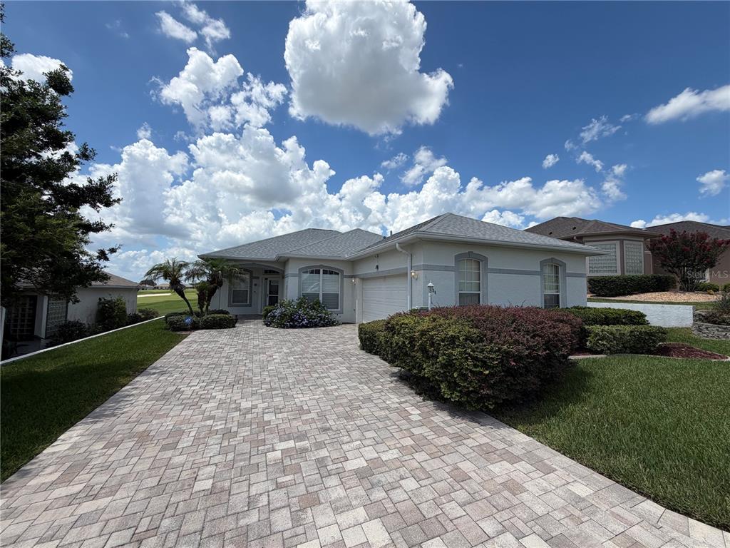 A single-story house with a paved driveway, a two-car garage, and landscaped front yard — 11734 SE 173RD LANE ROAD, SUMMERFIELD, FL