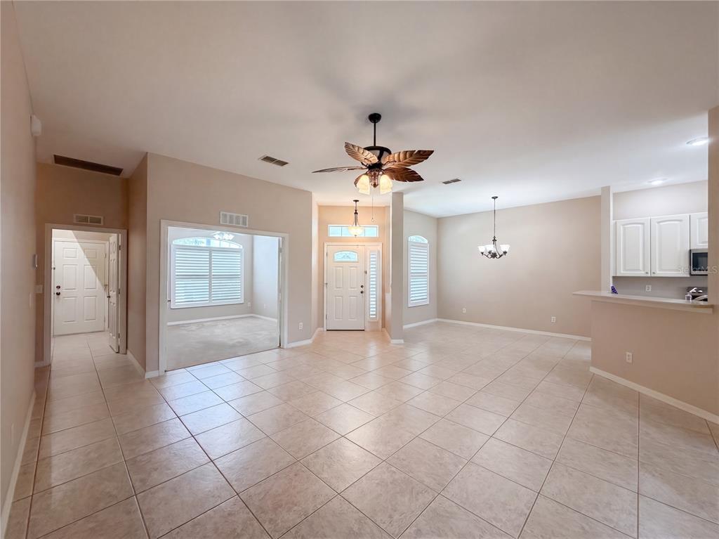 An open-concept living area features tile flooring, a palm-leaf ceiling fan, and an adjacent kitchen — 11734 SE 173RD LANE ROAD, SUMMERFIELD, FL