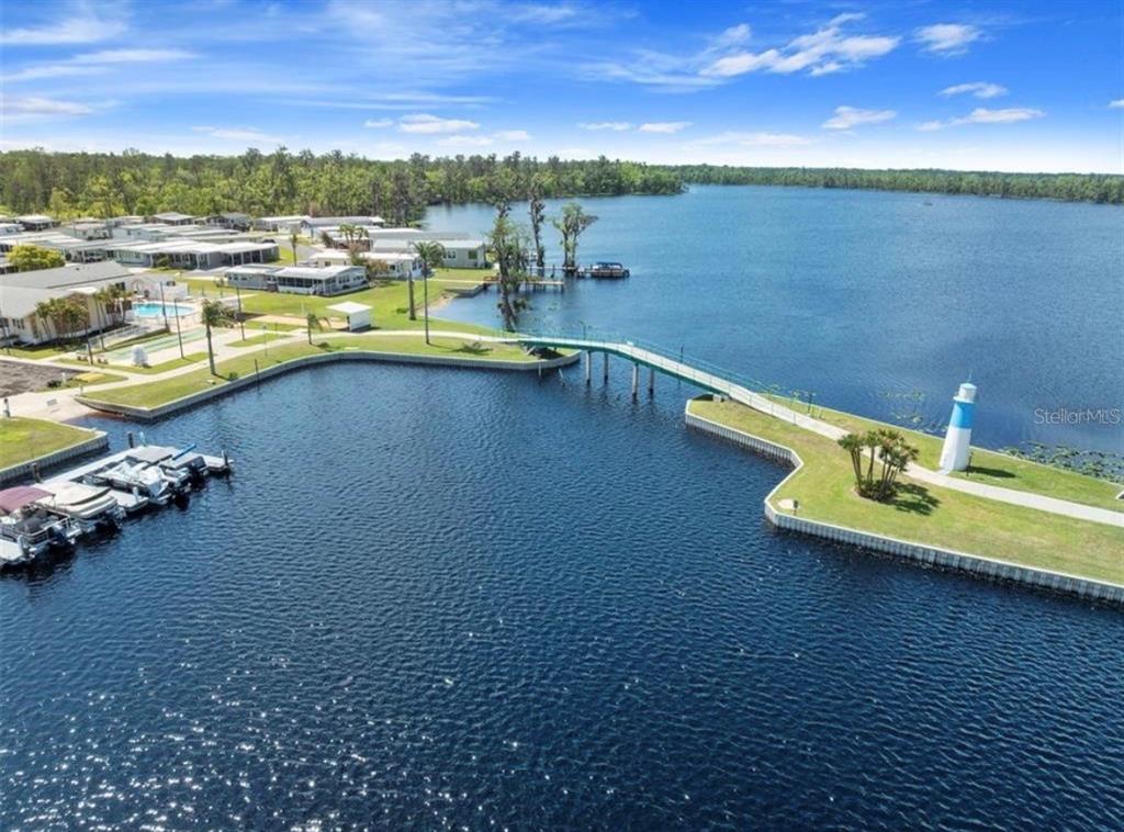 An aerial view shows a boat dock, a pedestrian bridge, and a lighthouse on a lake — 1401 W HIGHWAY 50 UNIT 179, CLERMONT, FL