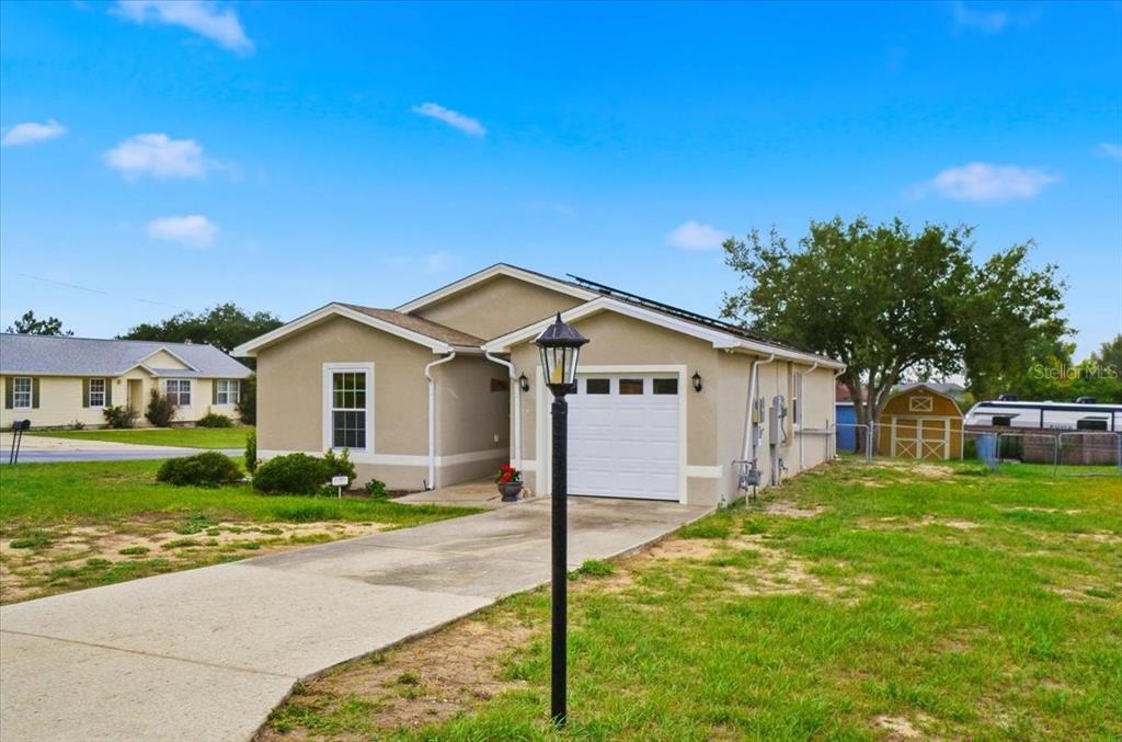 A tan single-story house with a white garage door and a flagpole in the yard — 115 SEMINOLE ROAD, BABSON PARK, FL