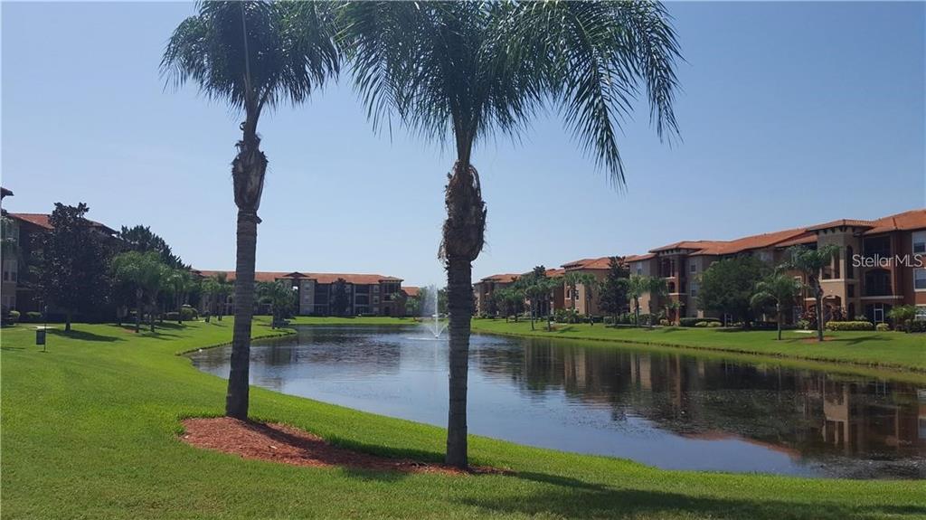 A pond with a fountain sits between apartment buildings and palm trees on a sunny day — 5554 METROWEST BOULEVARD UNIT 206, ORLANDO, FL