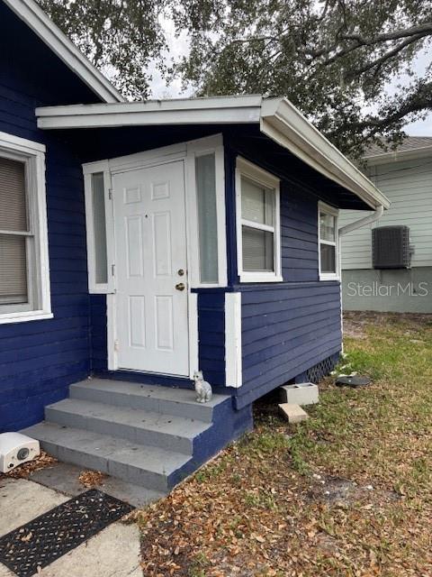 A blue house exterior features a white front door, concrete steps, and a small cat statue — 1815 2ND AVENUE E, BRADENTON, FL