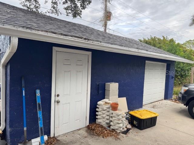 A blue exterior wall features a white door, a garage door, and stacked concrete blocks — 1815 2ND AVENUE E, BRADENTON, FL