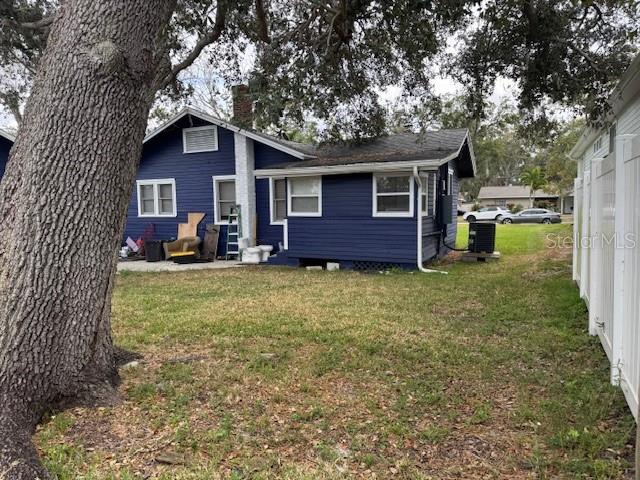 A blue house with white trim sits on a grassy lot under large oak trees — 1815 2ND AVENUE E, BRADENTON, FL