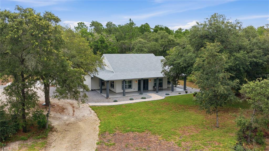 An aerial view of a single-story house with a gray roof and a wraparound porch — 18272 SW 65TH LOOP, DUNNELLON, FL