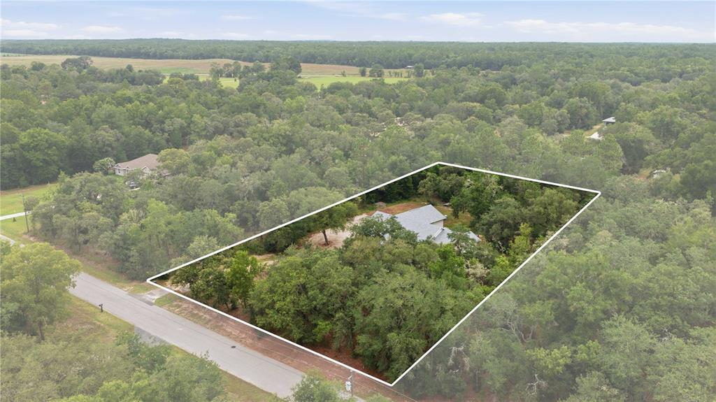 An aerial view shows a house nestled within a wooded lot along a paved road — 18272 SW 65TH LOOP, DUNNELLON, FL