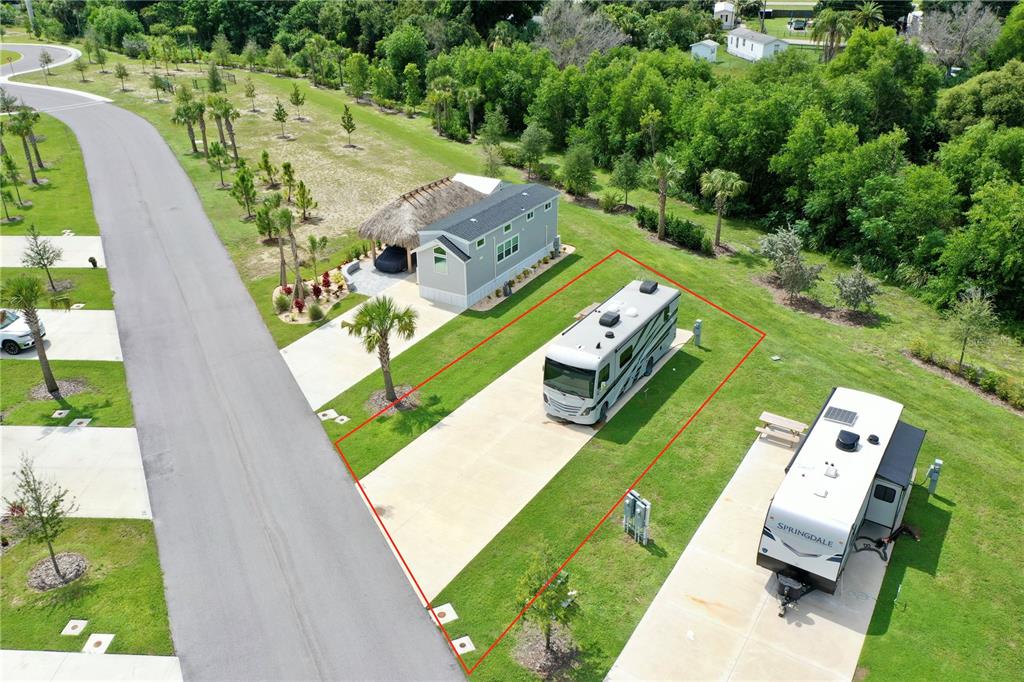 An aerial view shows a concrete RV pad with a motorhome in a landscaped park — 240 HORIZON ROAD, PUNTA GORDA, FL