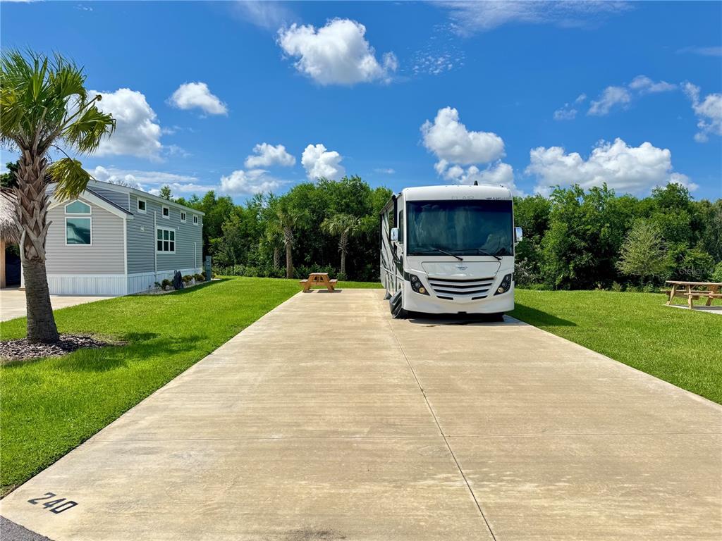 A white recreational vehicle is parked on a concrete pad next to a small house — 240 HORIZON ROAD, PUNTA GORDA, FL