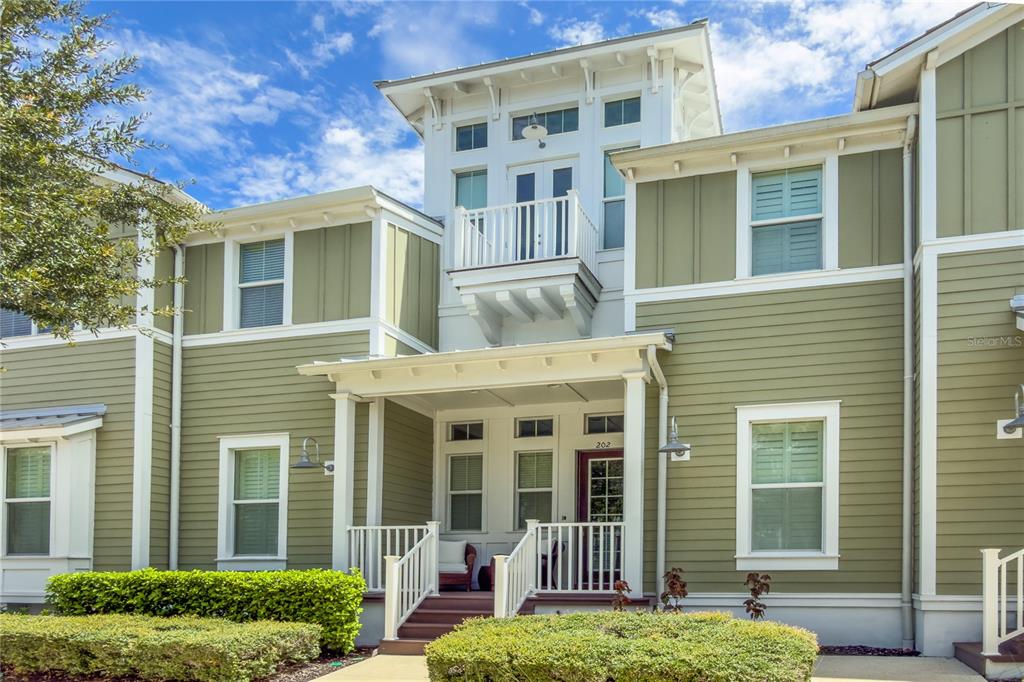 A two-story olive green house features a front porch, a balcony, and white trim — 311 SAPPHIRE LAKE DRIVE UNIT 202, BRADENTON, FL