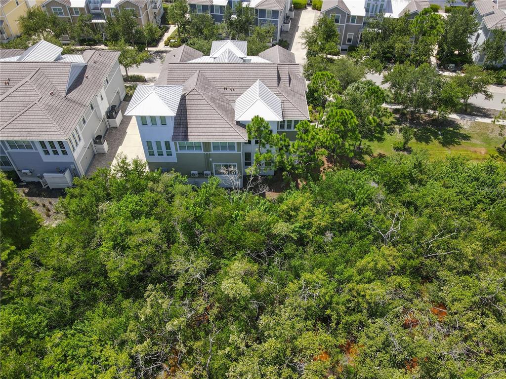 An aerial view shows two multi-story houses surrounded by dense green trees and landscaping — 311 SAPPHIRE LAKE DRIVE UNIT 202, BRADENTON, FL