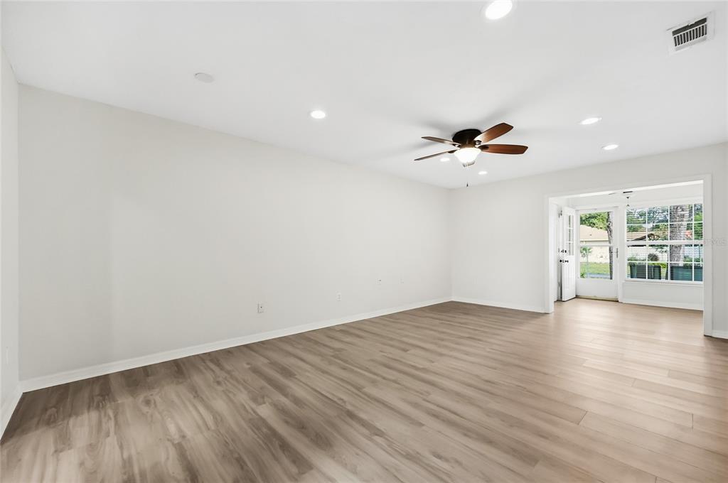 An entryway with light wood flooring leads to a living area with a ceiling fan — 249 N HILL AVENUE UNIT 30, DELAND, FL