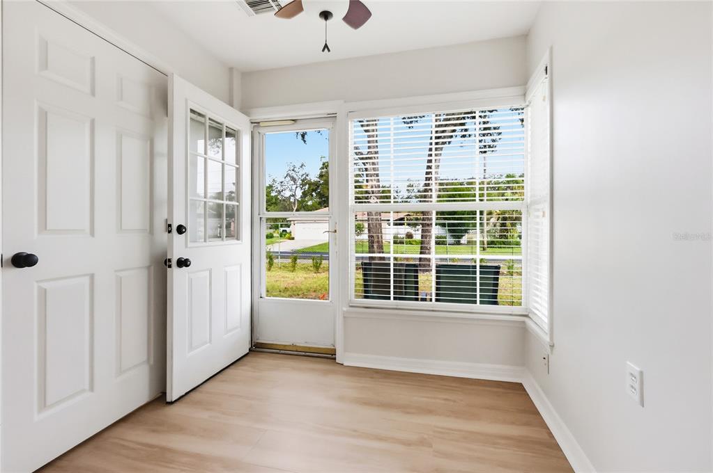 An empty room with light wood-look flooring, white walls, a ceiling fan, and a doorway — 249 N HILL AVENUE UNIT 30, DELAND, FL
