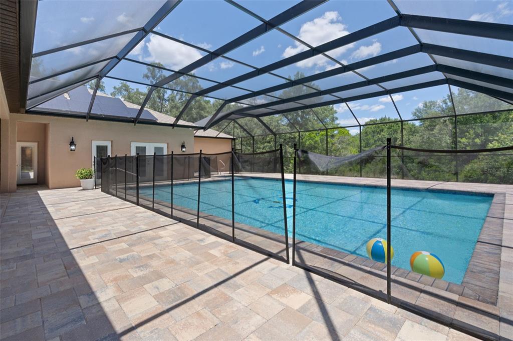A swimming pool with a safety fence is enclosed by a screened lanai — 222 SUNCOAST BOULEVARD, SPRING HILL, FL