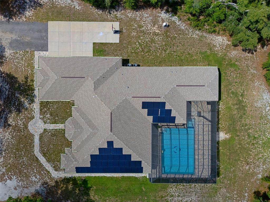 An aerial view shows a house with solar panels, a screened-in pool, and a driveway — 222 SUNCOAST BOULEVARD, SPRING HILL, FL
