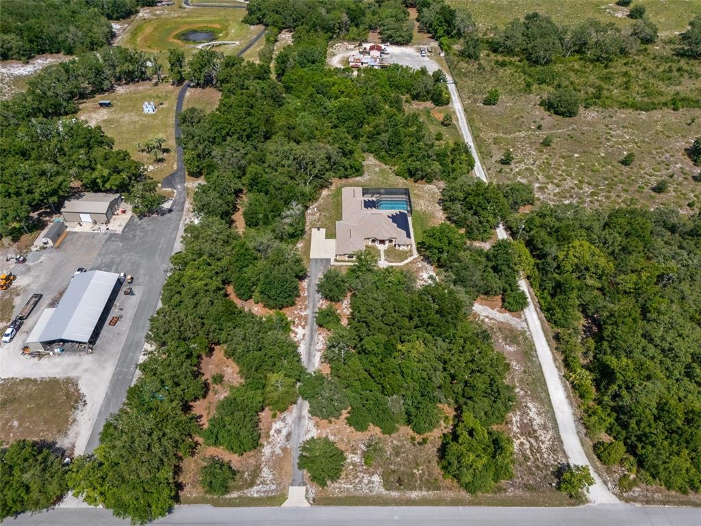 An aerial view shows a house with a pool surrounded by trees and driveways — 222 SUNCOAST BOULEVARD, SPRING HILL, FL