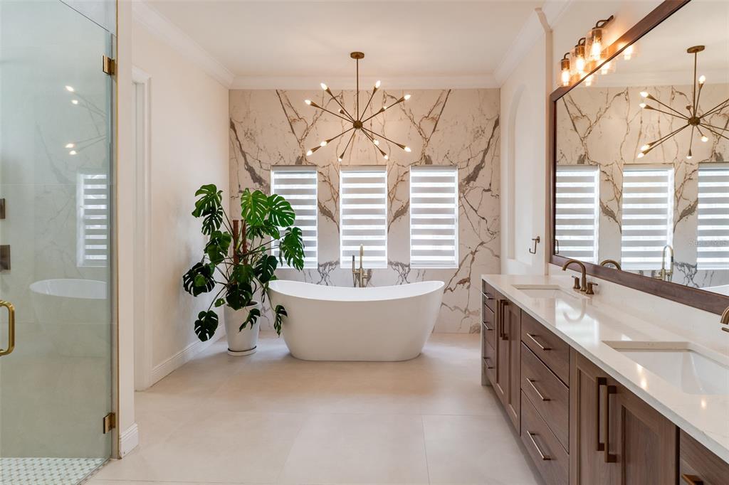 A dining room features a wooden table, modern chairs, two chandeliers, and large arched windows — 11027 HAWKSHEAD COURT, WINDERMERE, FL