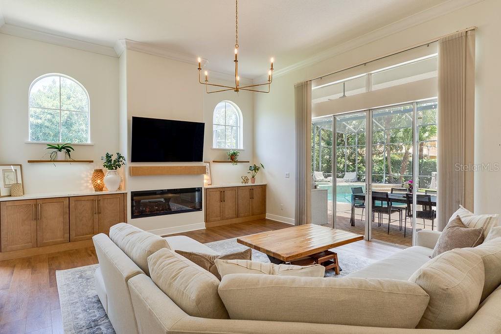 A living room features blue built-in bookshelves with a rolling ladder, two armchairs, and wood flooring — 11027 HAWKSHEAD COURT, WINDERMERE, FL