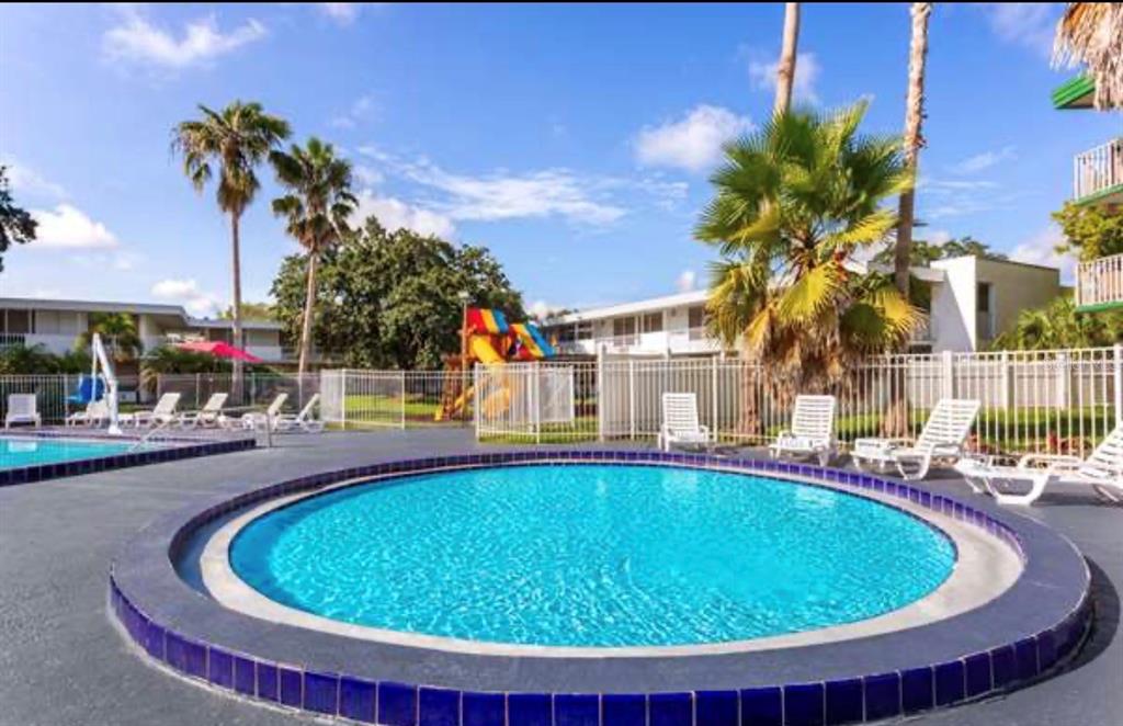 A circular swimming pool sits on a patio with lounge chairs and a playground nearby — 2930 NE POLYNESIAN ISLE UNIT 219, KISSIMMEE, FL