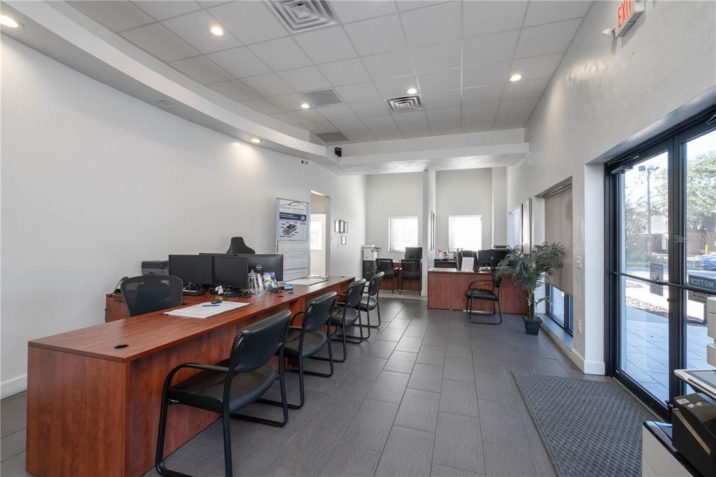 An office space features a long wooden desk, black chairs, and gray tile flooring — 1725 N MAIN STREET, GAINESVILLE, FL