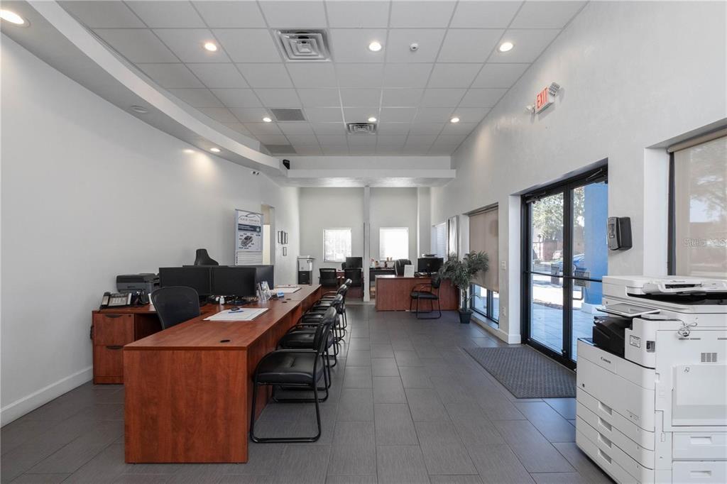An office interior features a long wooden desk, tiled floors, and a large printer — 1725 N MAIN STREET, GAINESVILLE, FL