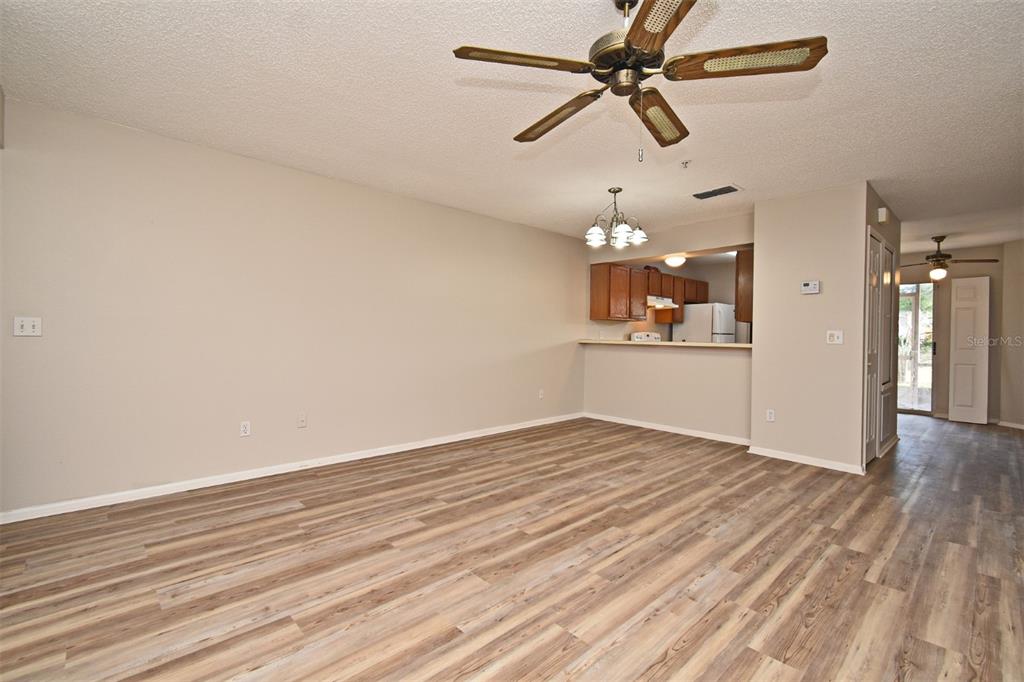 A living room with wood-look flooring, a ceiling fan, and an open kitchen pass-through — 144 RESERVE CIRCLE UNIT 112, OVIEDO, FL