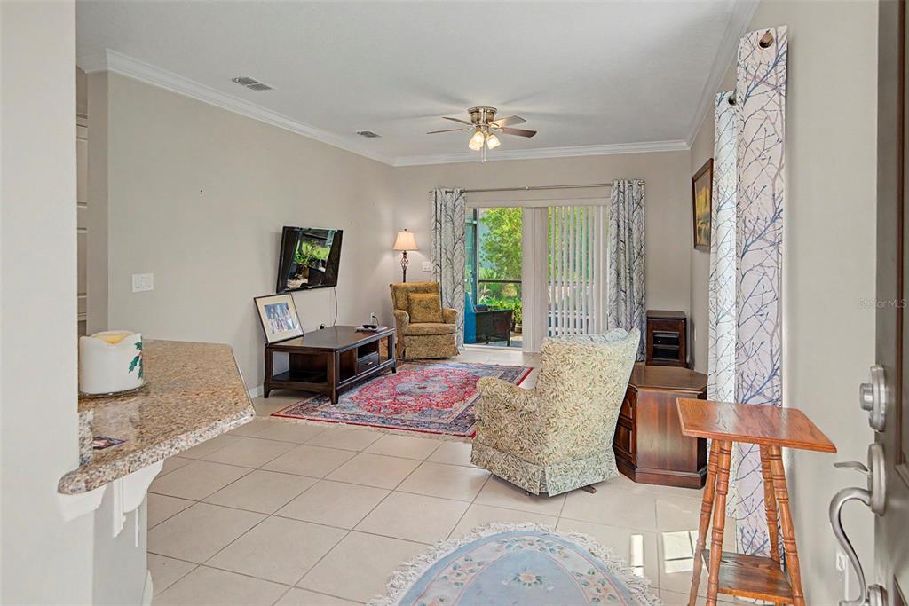 A living room features tile floors, a ceiling fan, a sliding glass door, and two armchairs — 284 VESTRELLA DRIVE, POINCIANA, FL