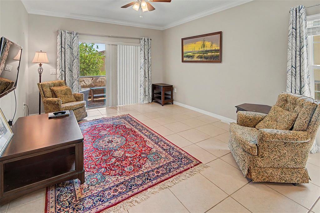 A living room features tile floors, a patterned area rug, two armchairs, and sliding glass doors — 284 VESTRELLA DRIVE, POINCIANA, FL