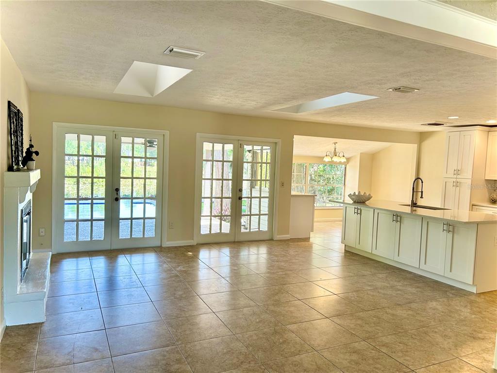 A bright living area with tile floors, two sets of French doors, and a kitchen — 17017 PAULA LANE, LUTZ, FL
