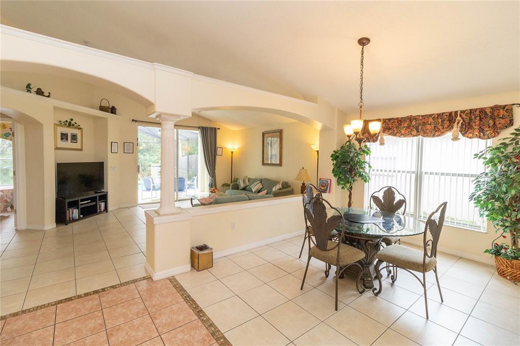A dining area with a glass table and chairs opens to a living room beyond — 4626 EAGLE PEAK DRIVE, KISSIMMEE, FL