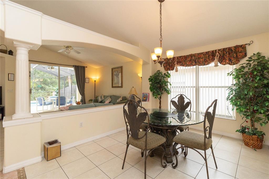 A dining area with a glass table and chairs opens into a living room space — 4626 EAGLE PEAK DRIVE, KISSIMMEE, FL