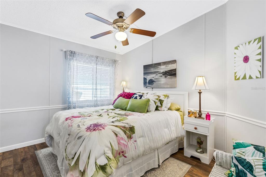 A bedroom features a floral comforter, a ceiling fan, and a white nightstand — 70 MOCKINGBIRD LANE, ELLENTON, FL