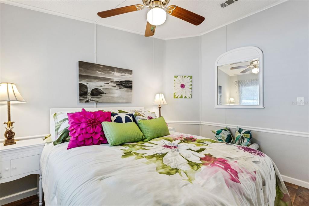 A bedroom features a floral comforter, a ceiling fan, and a mirror on the wall — 70 MOCKINGBIRD LANE, ELLENTON, FL