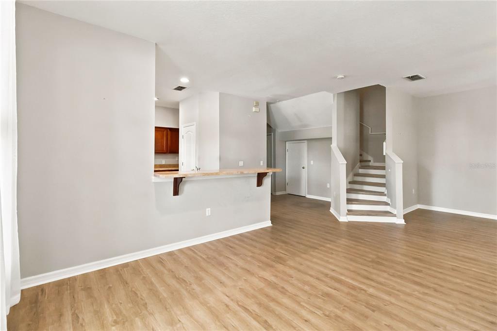 An interior view showing a living area with wood-look flooring, a breakfast bar, and stairs — 7103 RED LANTERN DRIVE UNIT 7103, HARMONY, FL