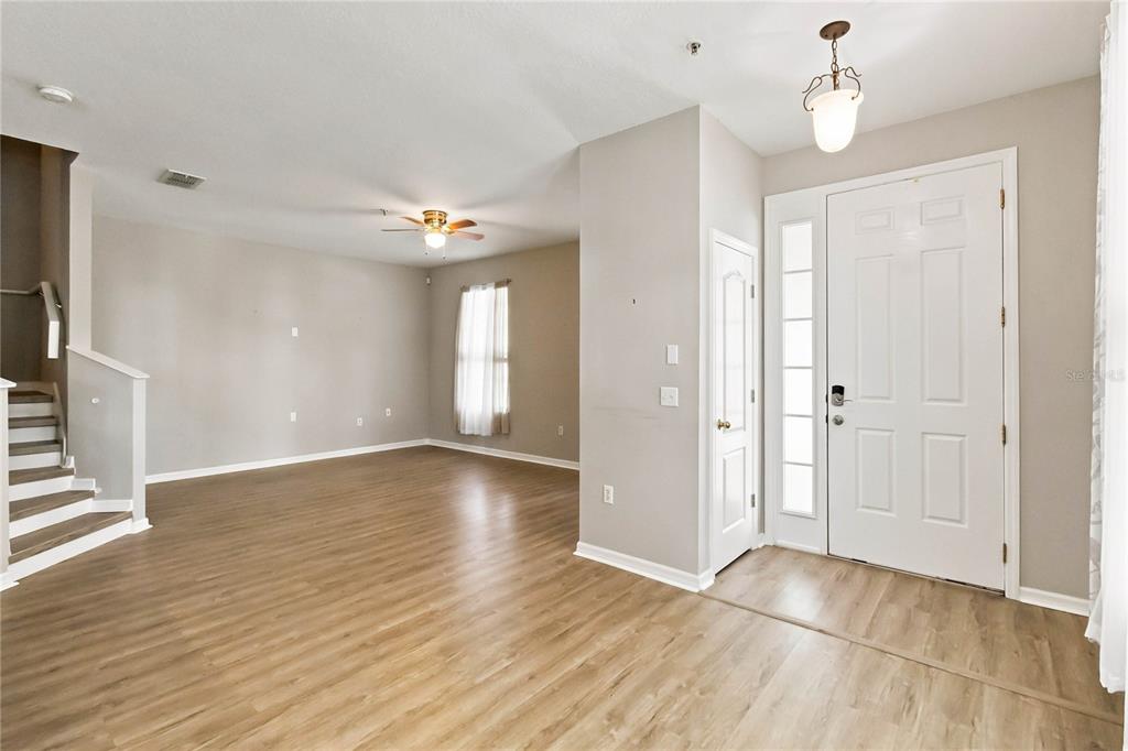 An entryway leads into a living room with light wood flooring and a staircase — 7103 RED LANTERN DRIVE UNIT 7103, HARMONY, FL