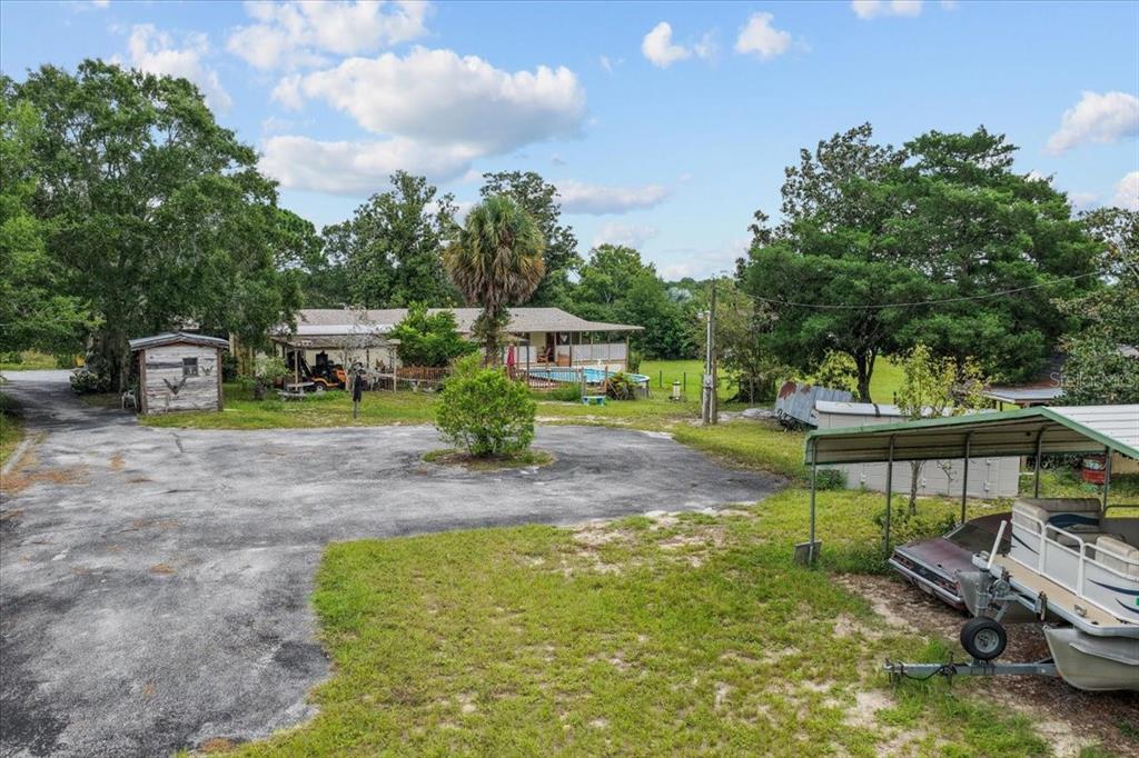 A yellow single-story mobile home sits next to a parked camper under mature trees — 470 FAY AVENUE, SPRING HILL, FL