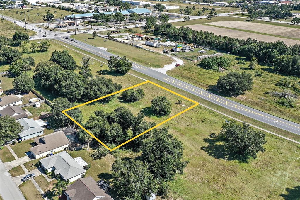 An aerial view shows a vacant, rectangular lot outlined in yellow next to a road — CR-448 Lot 3, TAVARES, FL