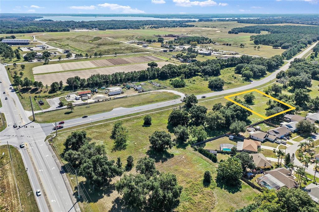 An aerial view shows a vacant, rectangular lot outlined in yellow near a suburban road — CR-448 Lot 3, TAVARES, FL