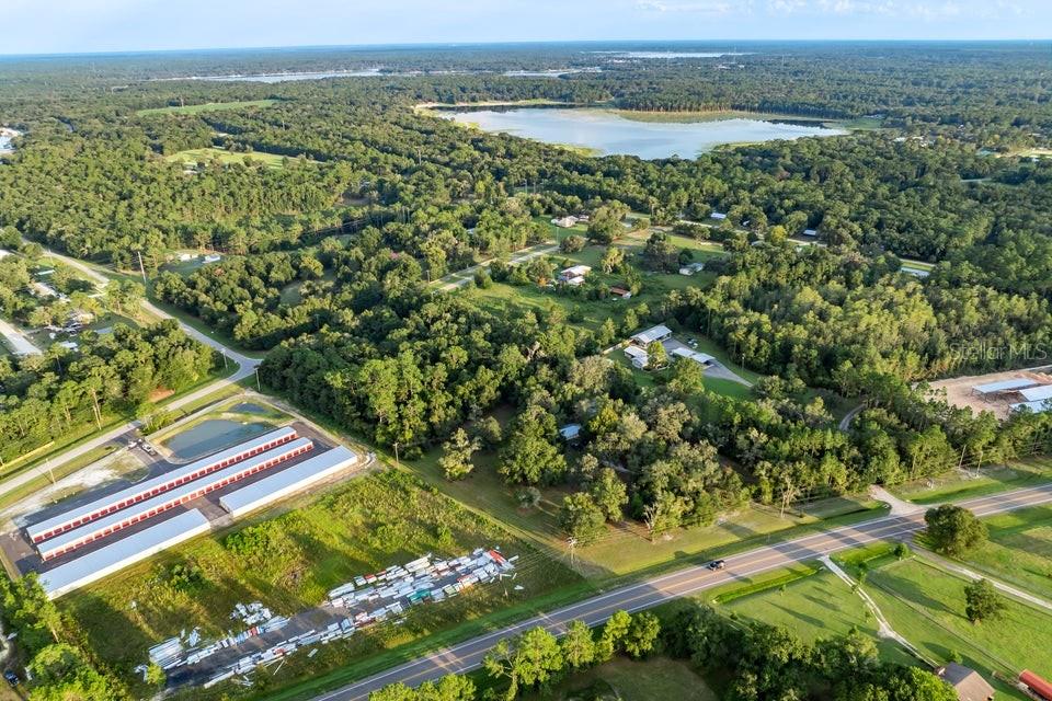 An aerial view shows a rural property with a storage facility, trees, and a lake — SE 9TH AVENUE, STARKE, FL
