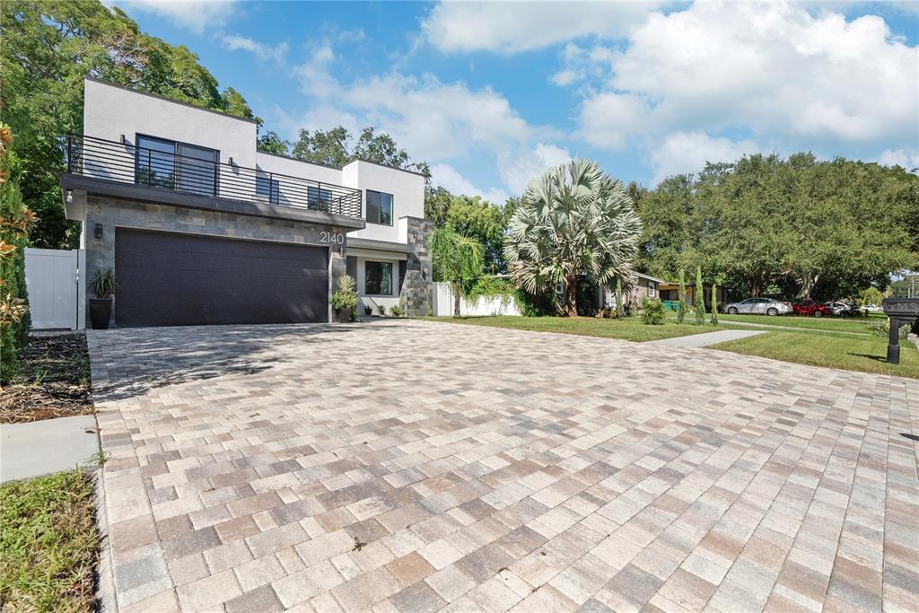 A modern two-story house features a large paver driveway and a dark garage door — 2140 CATALINA DRIVE, CLEARWATER, FL
