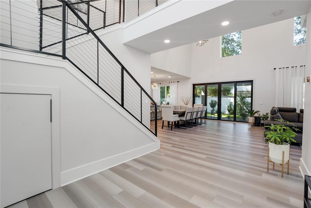 A modern, open-concept living and dining area features a staircase with black metal railings — 2140 CATALINA DRIVE, CLEARWATER, FL