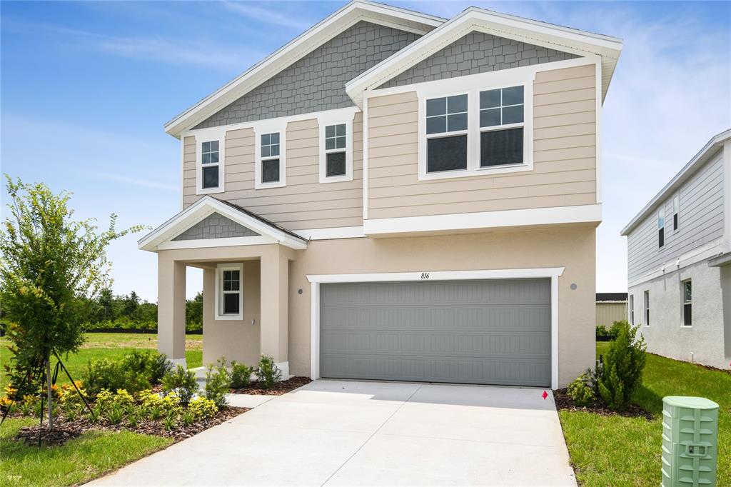 A two-story suburban house with a beige stucco exterior, gray shingle accents, and a garage — 816 LAKE DELL ROAD, DUNDEE, FL