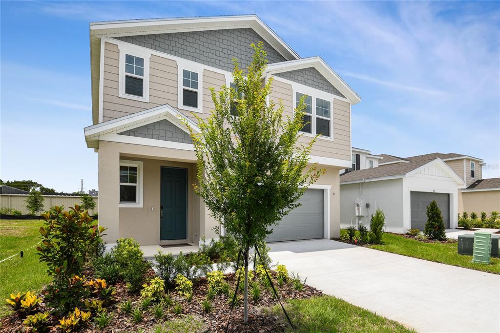 A two-story house with beige siding, gray shingles, and a front-facing garage under a blue sky — 816 LAKE DELL ROAD, DUNDEE, FL