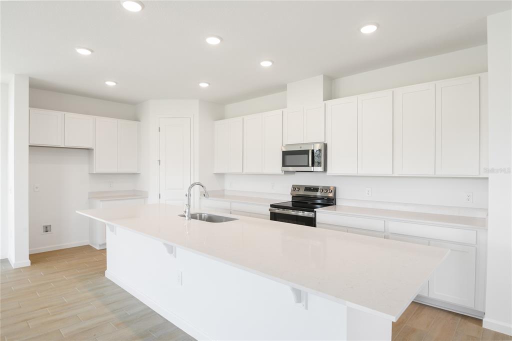 A modern kitchen features white cabinets, a large quartz island, and stainless steel appliances — 816 LAKE DELL ROAD, DUNDEE, FL