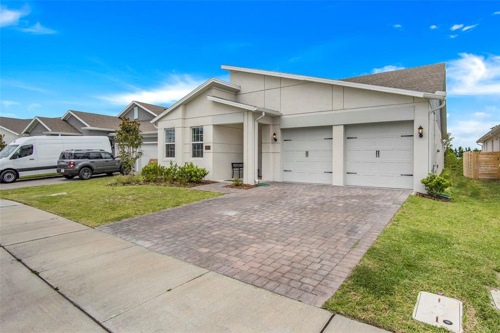 A single-story house with a two-car garage and a paved driveway under a blue sky — 18863 RAWSON STREET, ORLANDO, FL