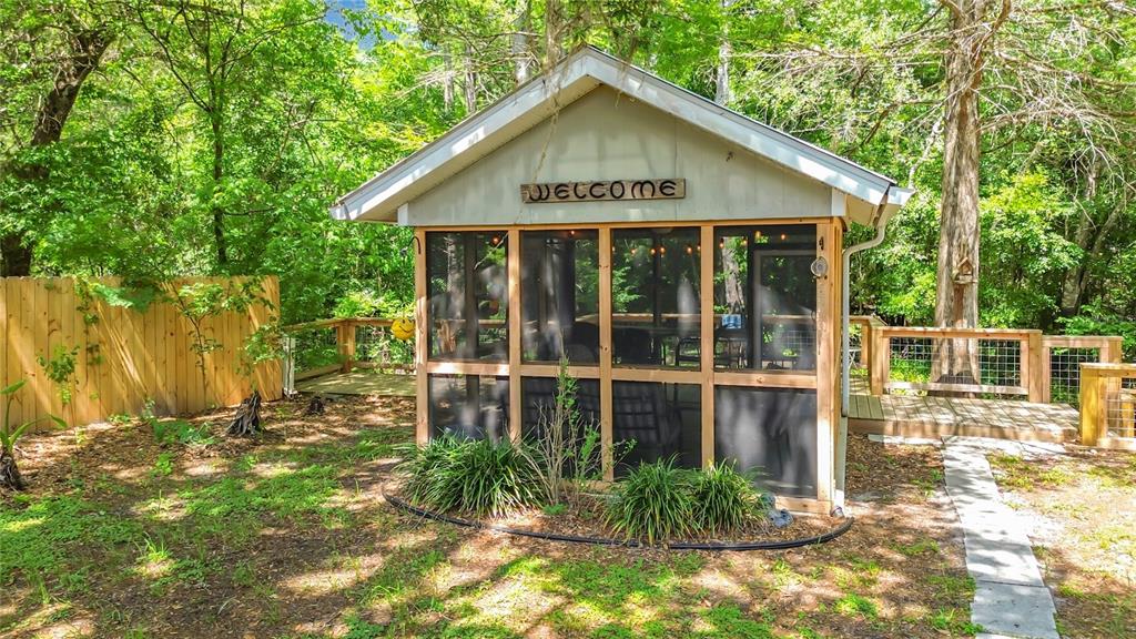 A wooden deck overlooks a shallow, tree-lined creek on a sunny day — 4129 E RIVERSIDE DRIVE, DUNNELLON, FL